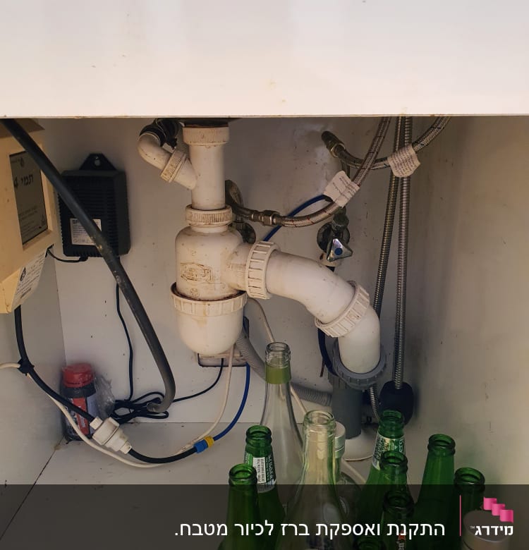 צנרת מתחת לכיור עם בקבוקי זכוכית